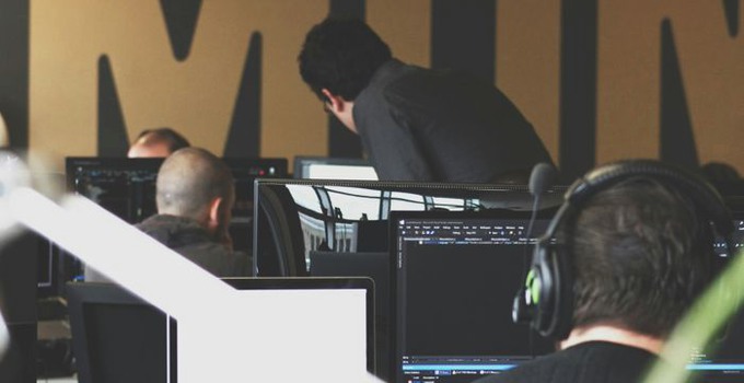 Tre män bakifrån som arbetar vid datorer.