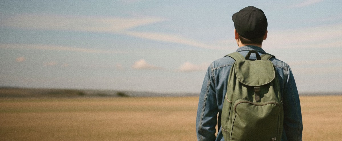 Male with back to camera look out over an open field.