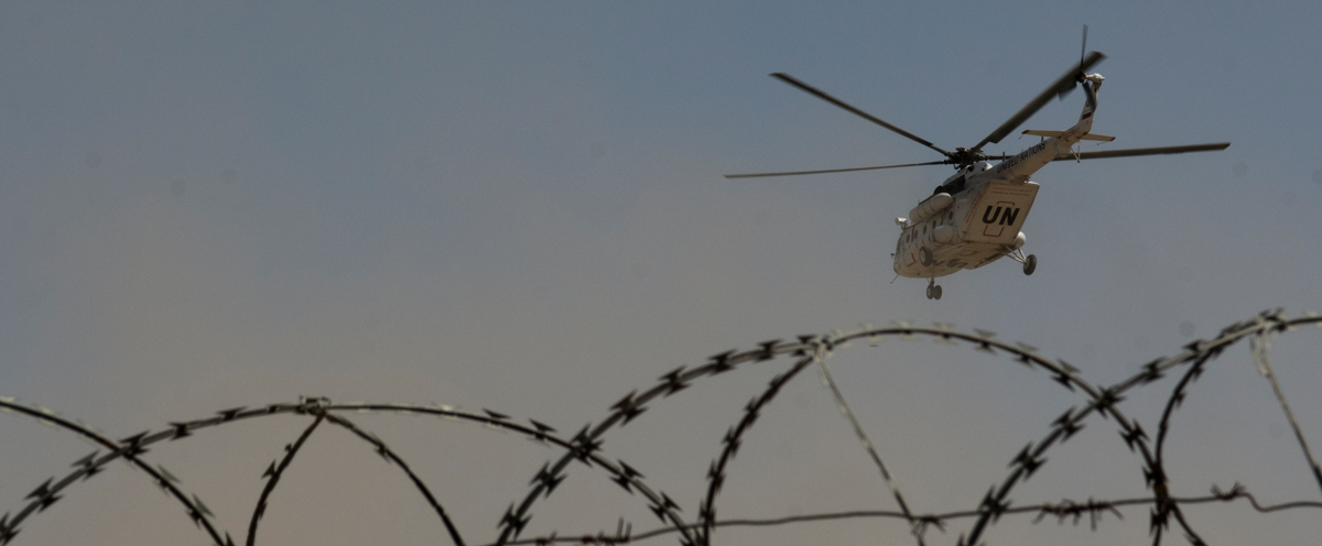 A helicopter flying over a barbed wire fence.