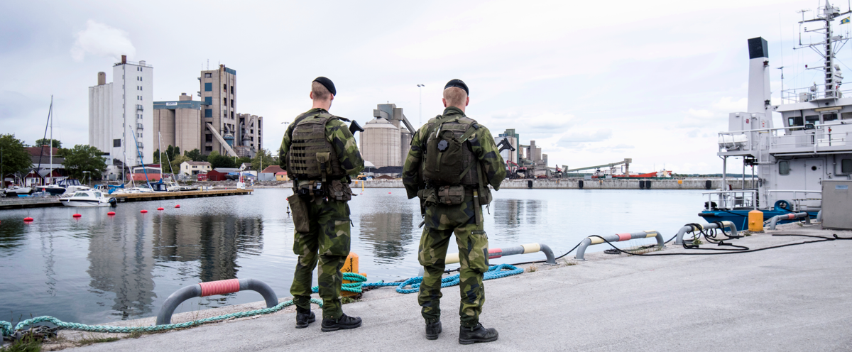 Two military men standing next to a body of water.