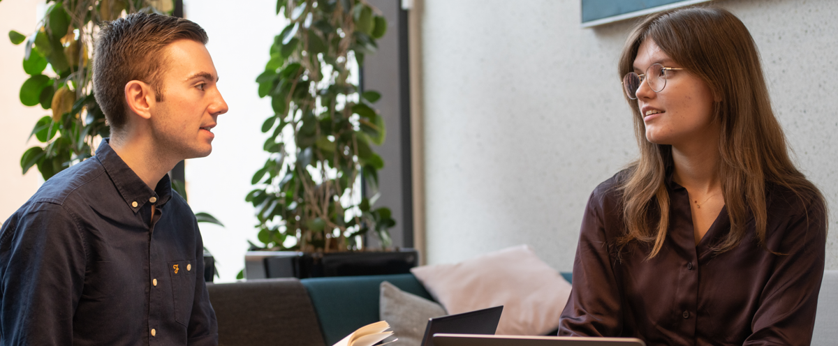 A man and a woman sitting at a table with laptops.