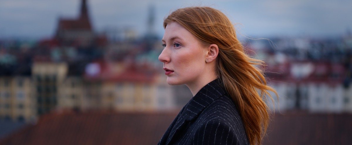 Kvinnlig student på Försvarshögskolans tak med blicken i fjärran.