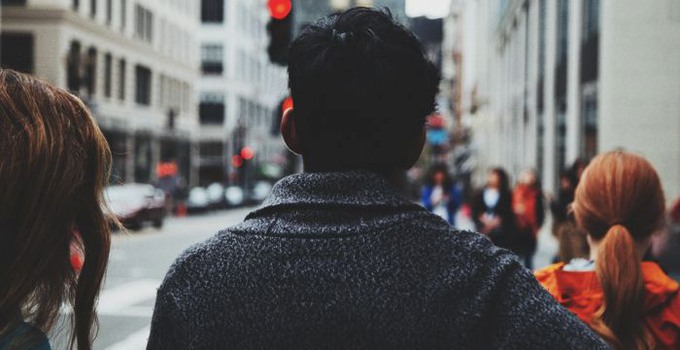 Människor bakifrån på en gata i en stad.