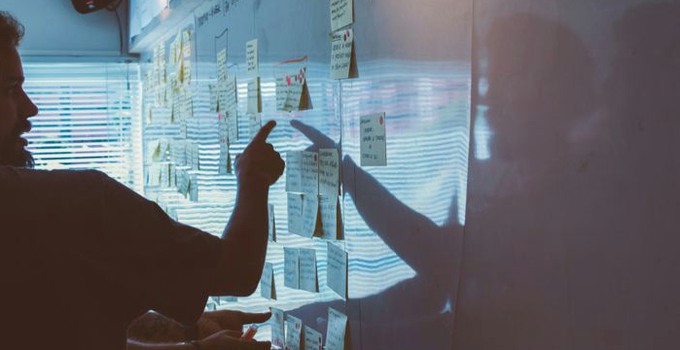 Person som pekar på en whiteboard med post-it-lappar.