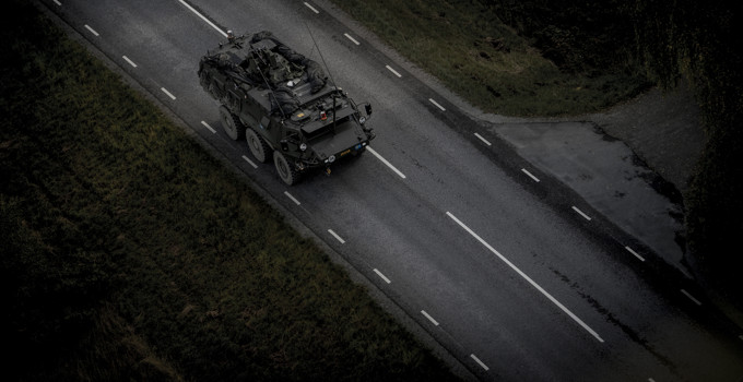 Ett militärfordon som kör längs en väg i mörkret.