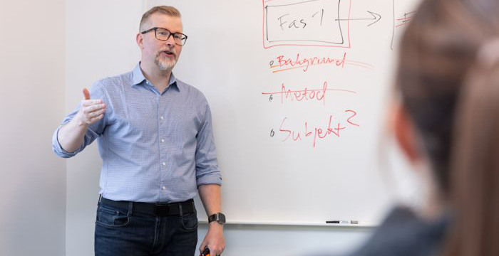 En man vid en whiteboard talar till publik