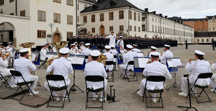 Musiker i vita uniformer framför Karlbergs slott. 