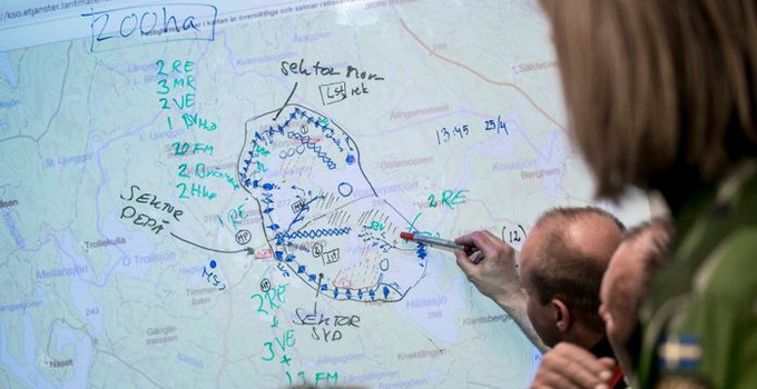 Personer som pekar på en whiteboard med en karta.