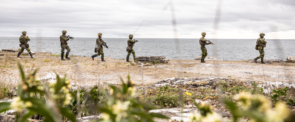 En grupp soldater som går över ett fält intill havet.
