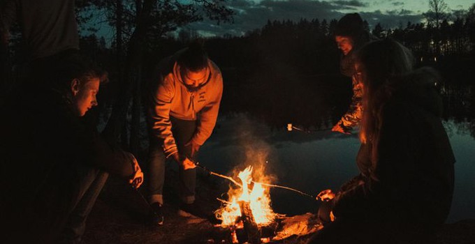 Fyra personer kring en lägereld.