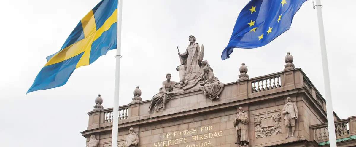 Riksdagshuset med svenska flaggan och EU-flaggan.