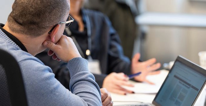 Ryggtavlan av en man framför laptop på utbildning.