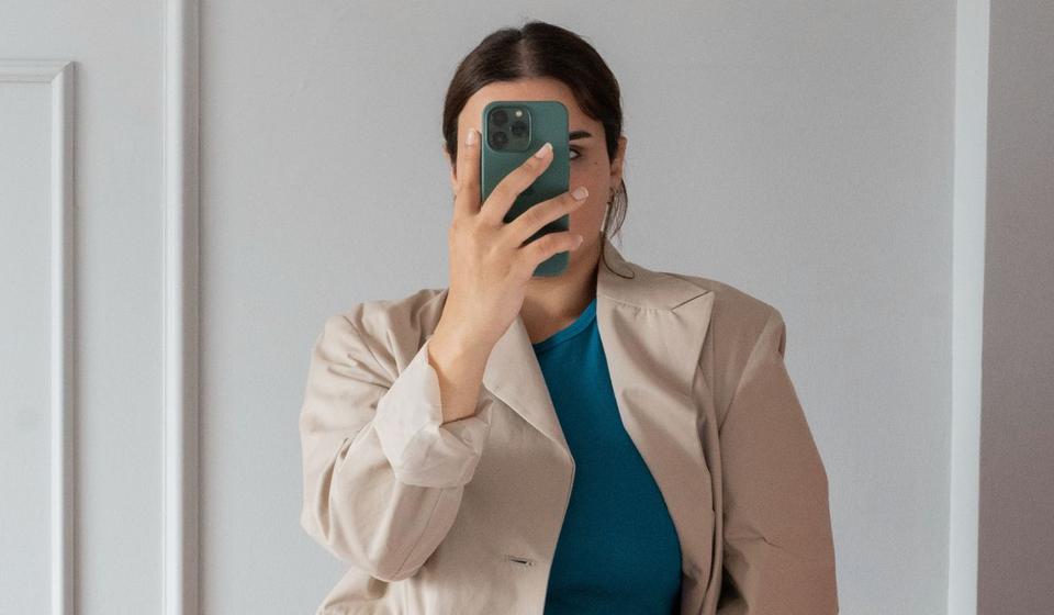 Kvinnlig student som fotar sig själv med mobiltelefonen.