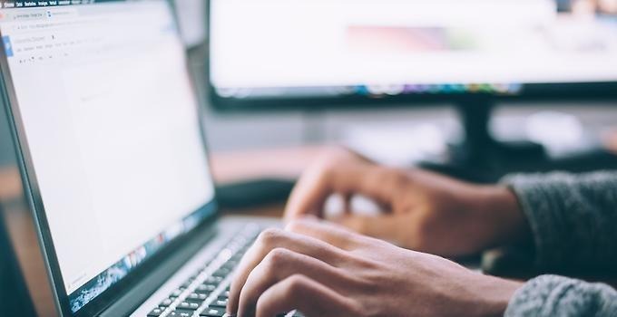 Närbild av hand som skriver på en dators tangentbord.