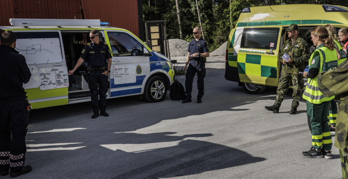 En grupp människor som står framför ambulanser.