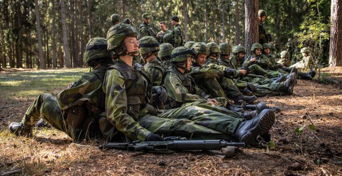 Soldater som sitter rygg mot rygg i skogen.