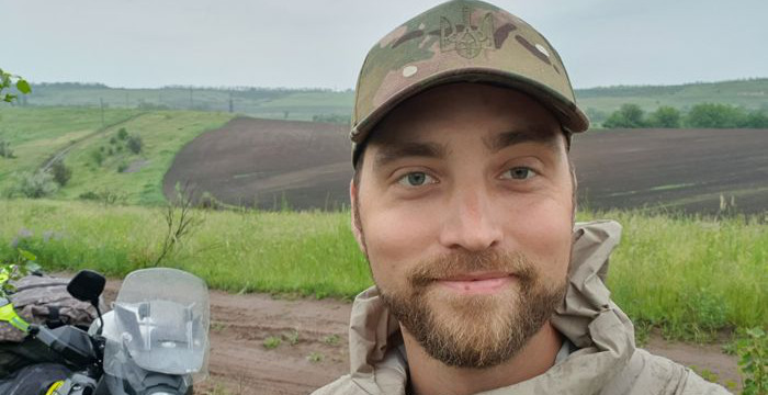 Porträtt av Daniel Smith med motorcykel i bakgrunden.