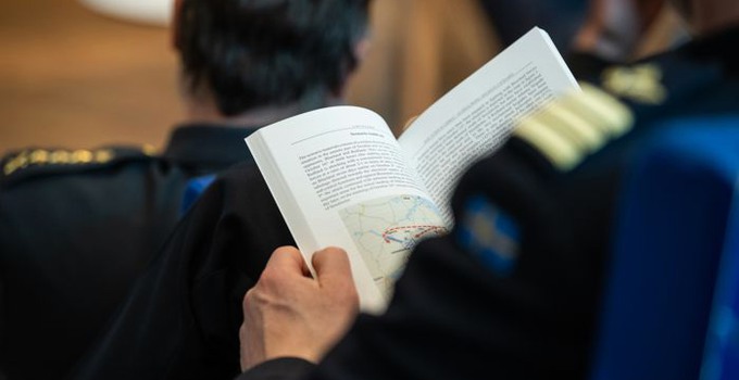 man bakifrån håller öppen bok