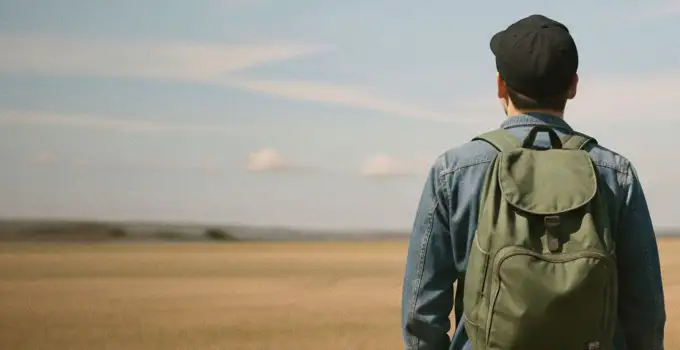 Manlig student med ryggen mot kameran och blickar mot horisonten.