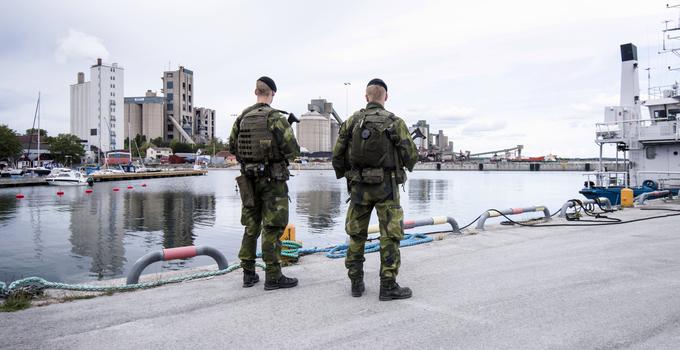 Två militärer med ryggen mot kameran på en kaj.
