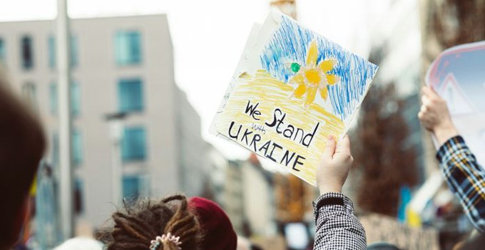 Hand som håller upp ett plakat för solidaritet med Ukraina under en demonstration.