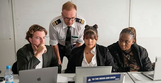 Studenter framför laptops under rollspel.