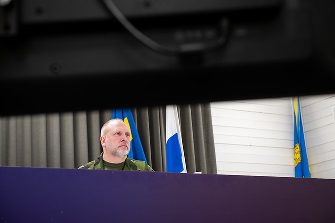 Person skymtar fram bakom två stora tv-skärmar.