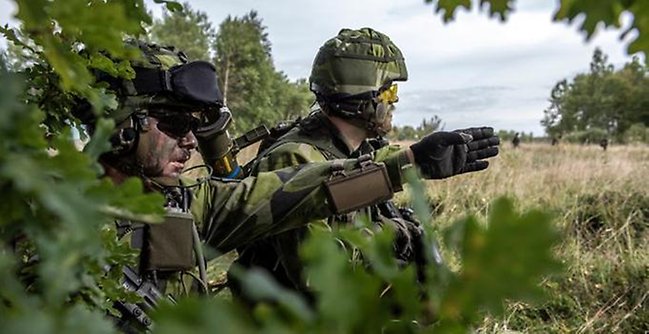 Två militärer under en övning utomhus.